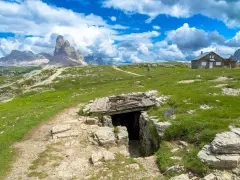 Un sentiero conduce a un rifugio di guerra sul Monte Piana, con le maestose Tre Cime di Lavaredo sullo sfondo.