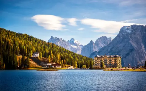 Paesaggio incantevole dei laghi del Veneto e Trentino, con un lago blu, montagne imponenti e un hotel storico.