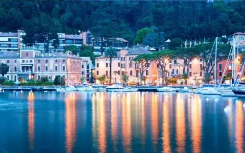 Il lungolago di Toscolano Maderno cosa vedere: hotel storici, palazzi colorati e barche a vela ormeggiate, con riflessi dorati sull'acqua.