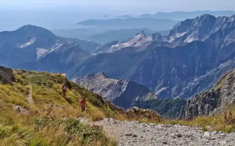 Due escursionisti affrontano la via Vandelli, un sentiero di montagna con notevole difficoltà, tra panorami mozzafiato e cave di marmo.