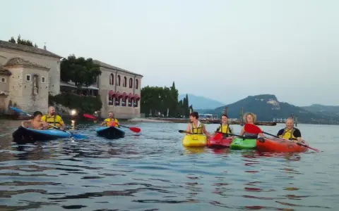 Persone in kayak sul lago verde, con un antico edificio sullo sfondo, vicino a San Vigilio di Marebbe.