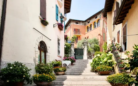 Un vicolo fiorito nel gardone riviera centro storico, con scale di pietra, case colorate e piante rigogliose.