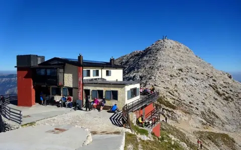 Rifugio Fraccaroli, un punto di ristoro in montagna. Per capire come arrivare, guarda la foto: un edificio con persone sedute all'esterno, con una vetta rocciosa sullo sfondo.