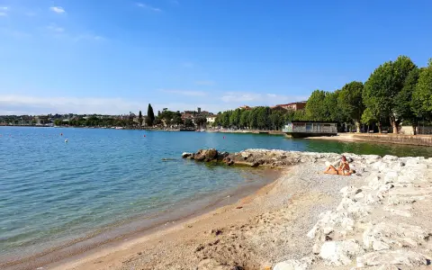 Spiaggia Desenzanino con persone che prendono il sole. Informazioni sui prezzi disponibili online per godersi il lago.