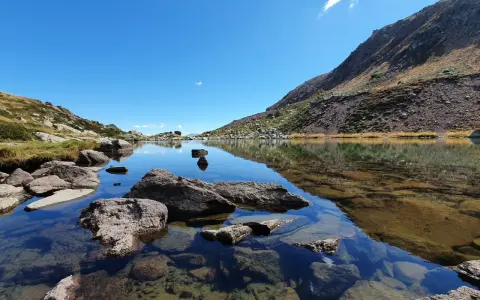 Laghi alpini cristallini vicino Vipiteno, con rocce affioranti e riflessi del cielo azzurro e delle montagne.