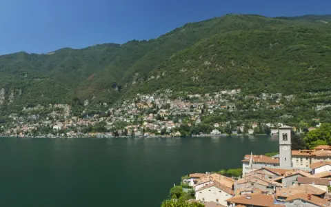 Un'ottima idea per sapere dove andare in montagna in Lombardia in giornata: un borgo pittoresco sul lago, con case colorate e montagne verdi sullo sfondo.