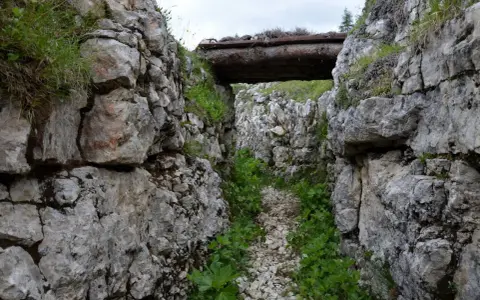 Trincea scavata nella roccia sul Monte Ortigara, con un tetto di tronchi. Per sapere come arrivare, cerca sentieri storici.