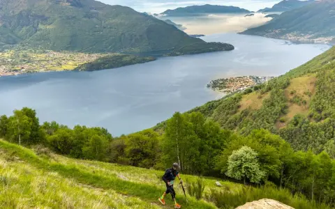 Un atleta corre su un sentiero erboso con vista sul Lago di Como, un'emozionante randonnée.