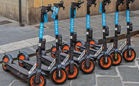 Monopattini elettrici Helbiz in fila, pronti per l'uso. La loro assicurazione è fondamentale per una mobilità sicura.