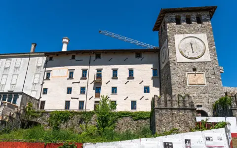 Torre dell'orologio e palazzi storici a Colloredo di Monte Albano, sotto un cielo azzurro.