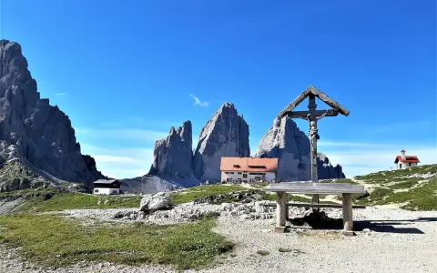 Croce e rifugio al cospetto delle Tre Cime di Lavaredo, un luogo iconico in Val Fiscalina.