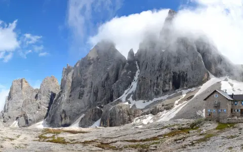 Rifugio Mulaz da Passo Valles, un'oasi di pietra tra le vette dolomitiche avvolte dalle nuvole.