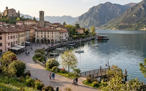 Pisogne: cosa vedere sul lago d'Iseo. Borgo con campanile, case colorate, lungolago con barche e montagne sullo sfondo.