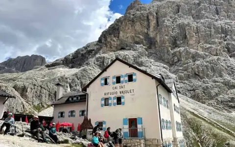 Rifugio Vajolet, punto di partenza per un percorso facile verso le Torri del Vajolet. Persone riposano sotto le imponenti rocce.
