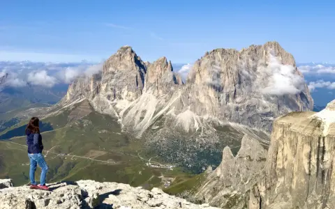 Ragazza ammira la terrazza delle Dolomiti. Per arrivare, prendi la funivia da Canazei.