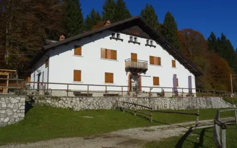Il rifugio Città di Vittorio Veneto, immerso nel foliage autunnale, accoglie con la sua facciata bianca e le finestre con persiane in legno.
