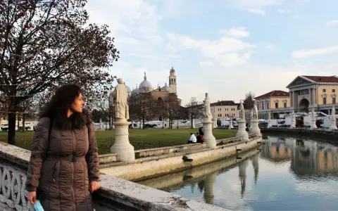 Una donna ammira il panorama di Padova in un giorno d'inverno, con statue, canali e la Basilica di Sant'Antonio sullo sfondo.