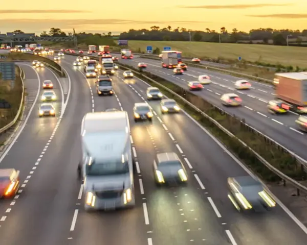 Traffico intenso su un'autostrada al tramonto. Auto e camion sfrecciano, creando scie luminose. Chissà se il limite velocità autostrada 150 dove è rispettato.