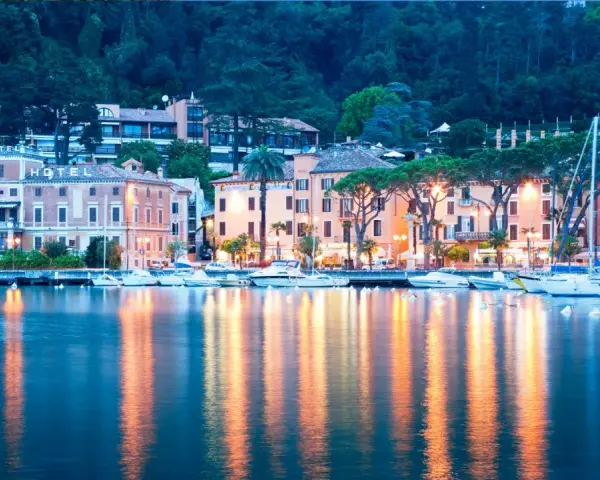 Il lungolago di Toscolano Maderno cosa vedere: hotel storici, palazzi colorati e barche a vela ormeggiate, con riflessi dorati sull'acqua.