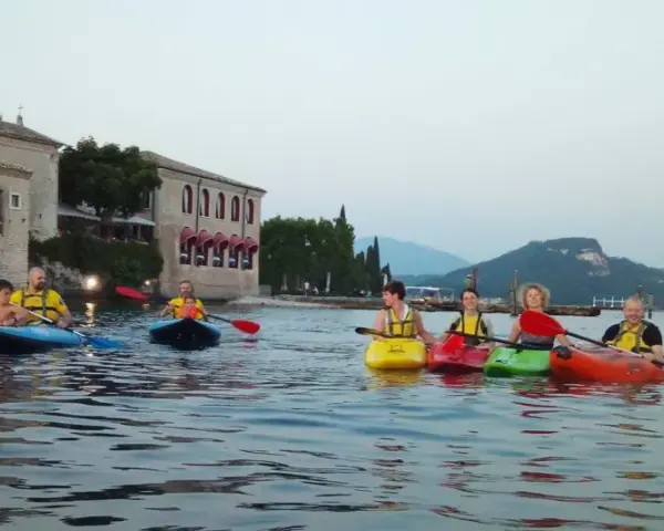 Persone in kayak sul lago verde, con un antico edificio sullo sfondo, vicino a San Vigilio di Marebbe.