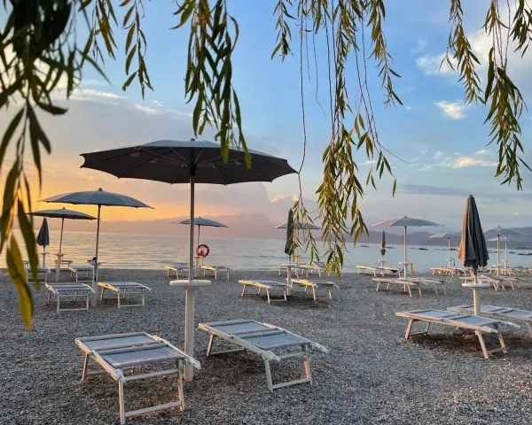 Alba sul lago di Garda, con lettini e ombrelloni pronti per accogliere i bagnanti sulle sue spiagge di sabbia.