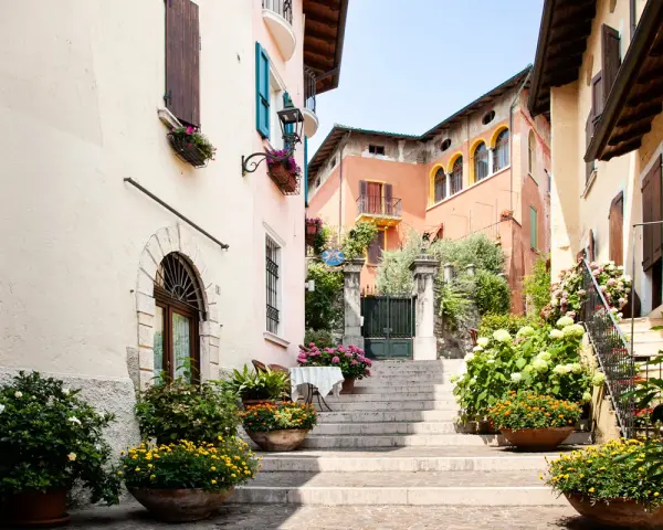 Un vicolo fiorito nel gardone riviera centro storico, con scale di pietra, case colorate e piante rigogliose.