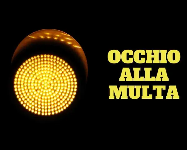 Semaforo giallo acceso, con la scritta "OCCHIO ALLA MULTA". Attenzione a non passare con il giallo, potresti ricevere una multa!