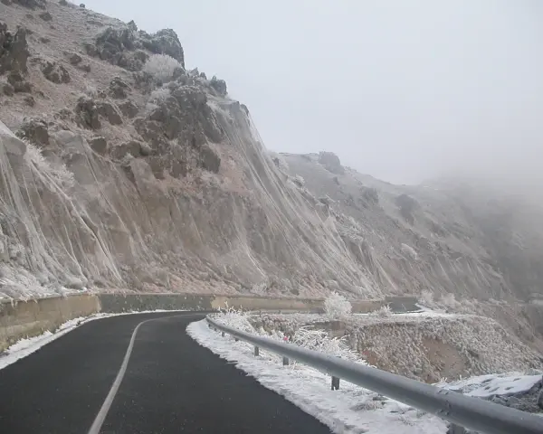 Strada innevata al passo del Faiallo, con rocce e vegetazione ghiacciate.