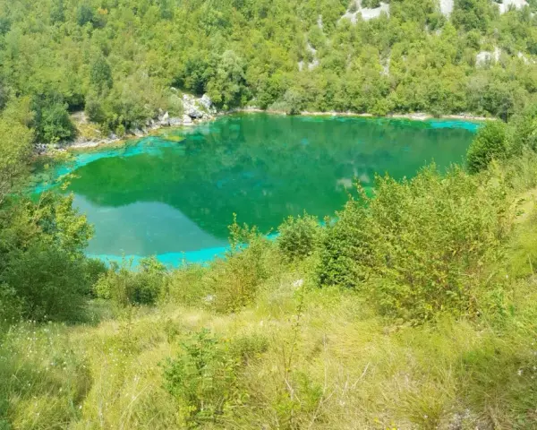 Lago di origine carsica a Forgaria nel Friuli, con acque cristalline di un verde smeraldo intenso, circondato da vegetazione lussureggiante.