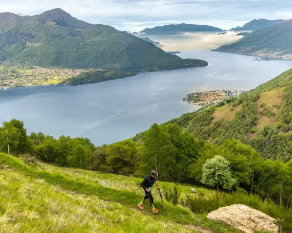 Un atleta corre su un sentiero erboso con vista sul Lago di Como, un'emozionante randonnée.