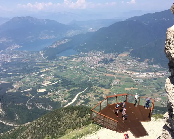 Vista panoramica dal Pizzo di Levico con un punto panoramico e persone che ammirano la valle sottostante.