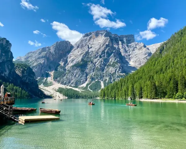 Barche sul **Pragser Wildsee** con montagne imponenti e foreste verdi.