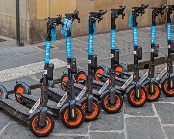 Monopattini elettrici Helbiz in fila, pronti per l'uso. La loro assicurazione è fondamentale per una mobilità sicura.