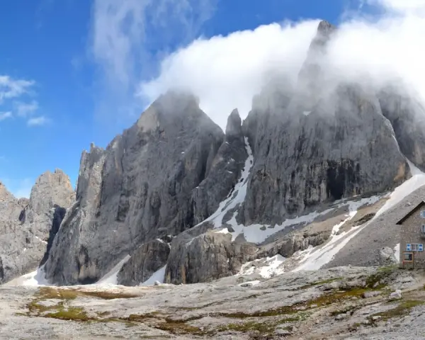 Rifugio Mulaz da Passo Valles, un'oasi di pietra tra le vette dolomitiche avvolte dalle nuvole.