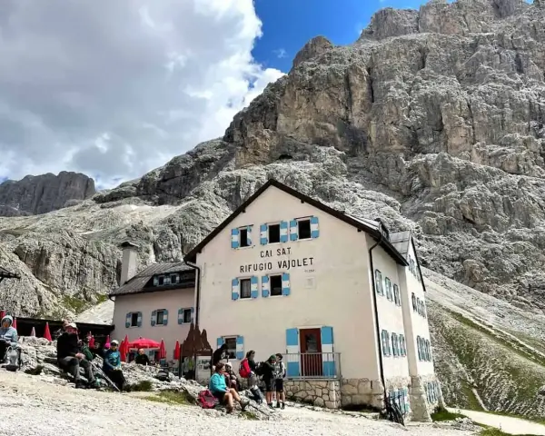 Rifugio Vajolet, punto di partenza per un percorso facile verso le Torri del Vajolet. Persone riposano sotto le imponenti rocce.
