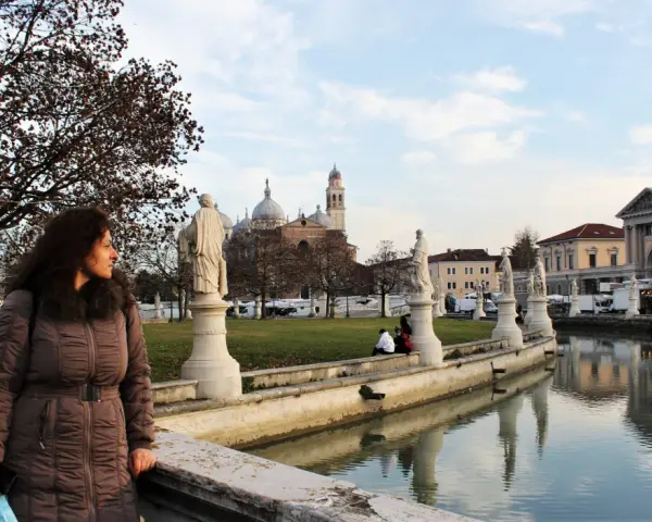 Una donna ammira il panorama di Padova in un giorno d'inverno, con statue, canali e la Basilica di Sant'Antonio sullo sfondo.
