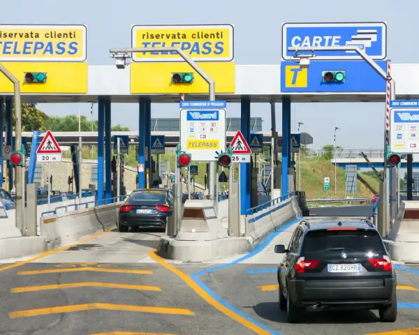 Casello autostradale con corsie Telepass e carte. Un'auto nera attende, forse per un mancato pagamento Telepass senza ricevuta.
