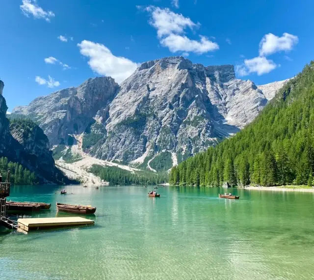 Barche sul **Pragser Wildsee** con montagne imponenti e foreste verdi.