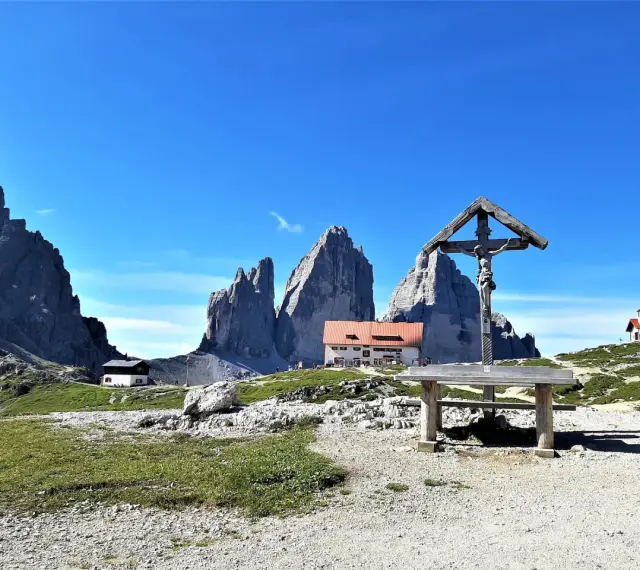 Croce e rifugio al cospetto delle Tre Cime di Lavaredo, un luogo iconico in Val Fiscalina.