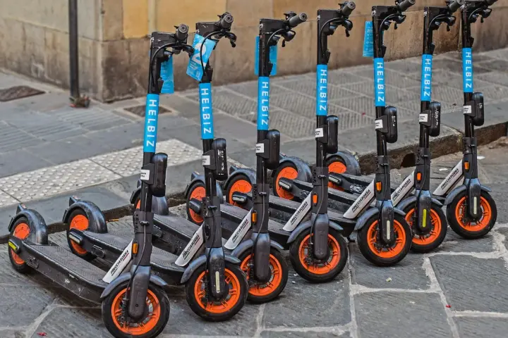 Monopattini elettrici Helbiz in fila, pronti per l'uso. La loro assicurazione è fondamentale per una mobilità sicura.