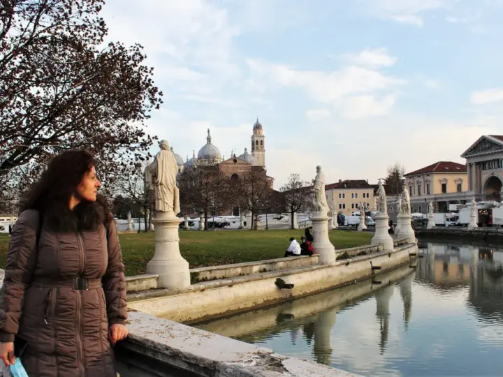 Una donna ammira il panorama di Padova in un giorno d'inverno, con statue, canali e la Basilica di Sant'Antonio sullo sfondo.