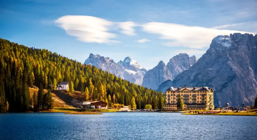 Paesaggio incantevole dei laghi del Veneto e Trentino, con un lago blu, montagne imponenti e un hotel storico.