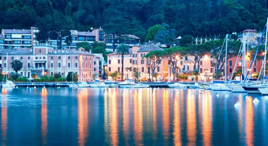 Il lungolago di Toscolano Maderno cosa vedere: hotel storici, palazzi colorati e barche a vela ormeggiate, con riflessi dorati sull'acqua.