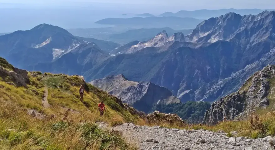 Due escursionisti affrontano la via Vandelli, un sentiero di montagna con notevole difficoltà, tra panorami mozzafiato e cave di marmo.