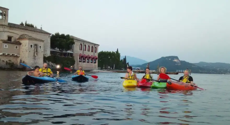 Persone in kayak sul lago verde, con un antico edificio sullo sfondo, vicino a San Vigilio di Marebbe.