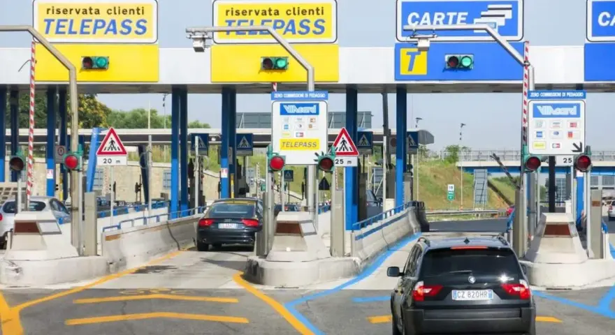Casello autostradale con corsie Telepass e carte. Un'auto nera si avvicina, sperando che il suo Telepass non funzioni per evitare una multa.