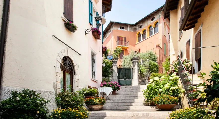 Un vicolo fiorito nel gardone riviera centro storico, con scale di pietra, case colorate e piante rigogliose.
