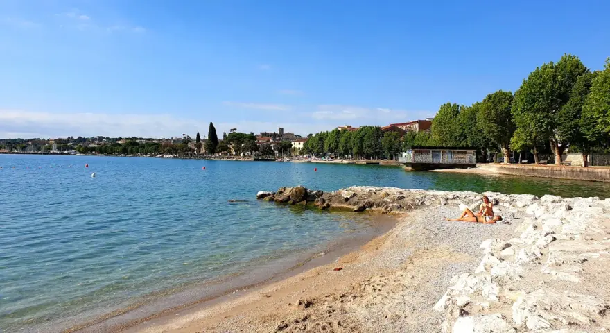 Spiaggia Desenzanino con persone che prendono il sole. Informazioni sui prezzi disponibili online per godersi il lago.