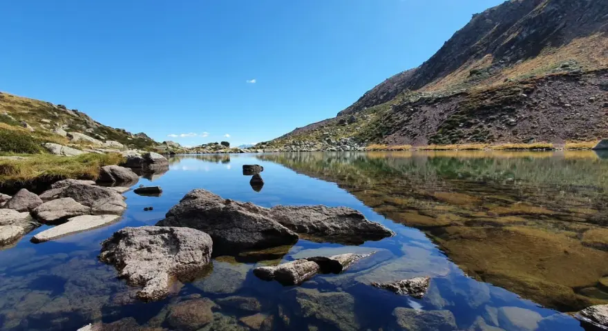 Laghi alpini cristallini vicino Vipiteno, con rocce affioranti e riflessi del cielo azzurro e delle montagne.
