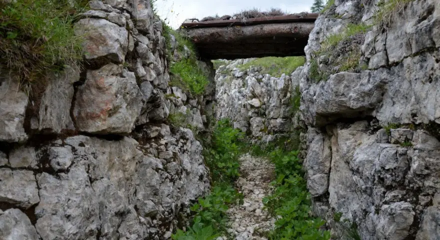 Trincea scavata nella roccia sul Monte Ortigara, con un tetto di tronchi. Per sapere come arrivare, cerca sentieri storici.
